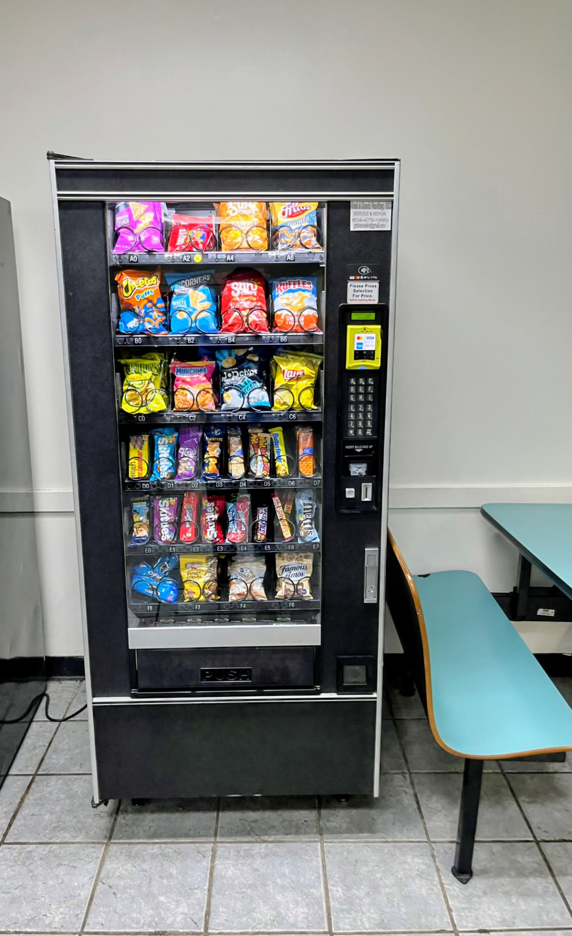 Glass-front snack vending machine stocked with chips, candy, and cookies